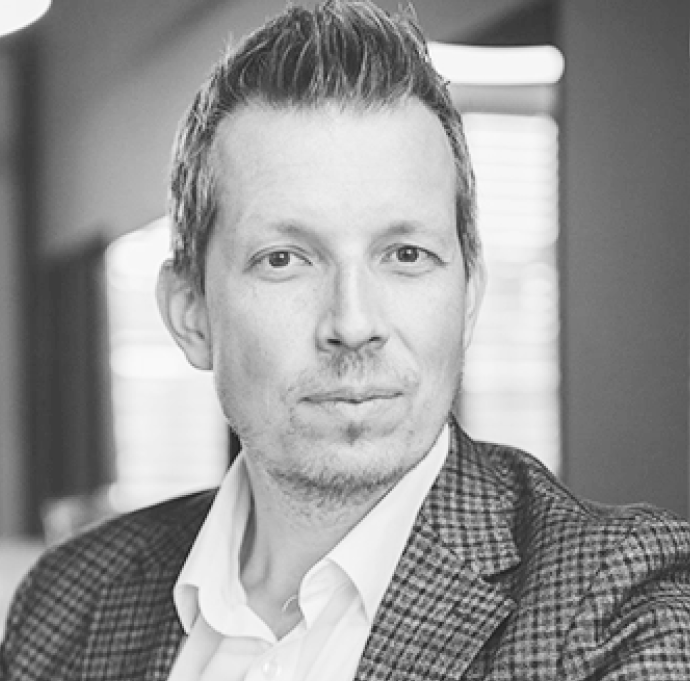 Portrait of a woman with brown hair on a flat gray background.